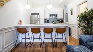 A modern kitchen with white cabinets, stainless steel appliances, and a central island with bar stools. - 2BR w/Balcony Fairmount Park 10 mins to DT (Philadelphia)