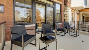 A covered outdoor seating area with wicker chairs and a small table, large windows, and a brick building facade. - 2BR w/Balcony Fairmount Park 10 mins to DT (Philadelphia)