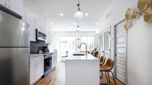Cocina moderna con electrodomésticos de acero inoxidable, una isla central y un comedor con sillas de cuero.