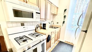 Une cuisine de taille réduite, équipée d’une cuisinière, d’un four à micro-ondes et d’un évier.