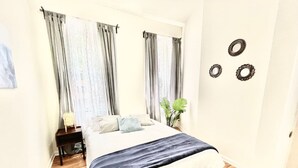 Une chambre à coucher avec un lit, des rideaux, une table de chevet et des éléments de décoration murale.