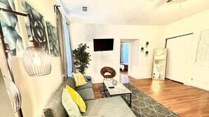 Un salon moderne avec un canapé gris, une table basse et un téléviseur fixé au mur.