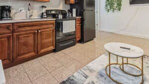 A kitchen with wooden cabinets, a black refrigerator, and a white countertop. - Across from Convention Center | Sleeps 6 | 3F (Philadelphia)