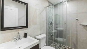 Une salle de bain moderne avec une douche à parois de verre, un lavabo blanc et des toilettes.
