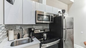 A modern kitchen with stainless steel appliances, a gas stove, a microwave, and a refrigerator.