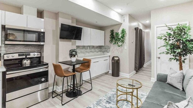A modern kitchen with a dining area, a sofa, and a plant.