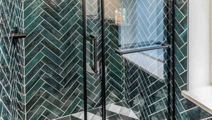 Een moderne badkamer met een douchecabine van glas en een vloer betegeld met geometrische tegels.