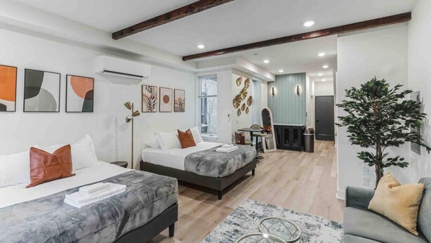 Een moderne hotelkamer met twee bedden, een zithoek en uitzicht op de gang.