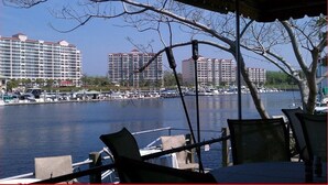 A waterfront restaurant with outdoor seating overlooking a marina and high-rise buildings.