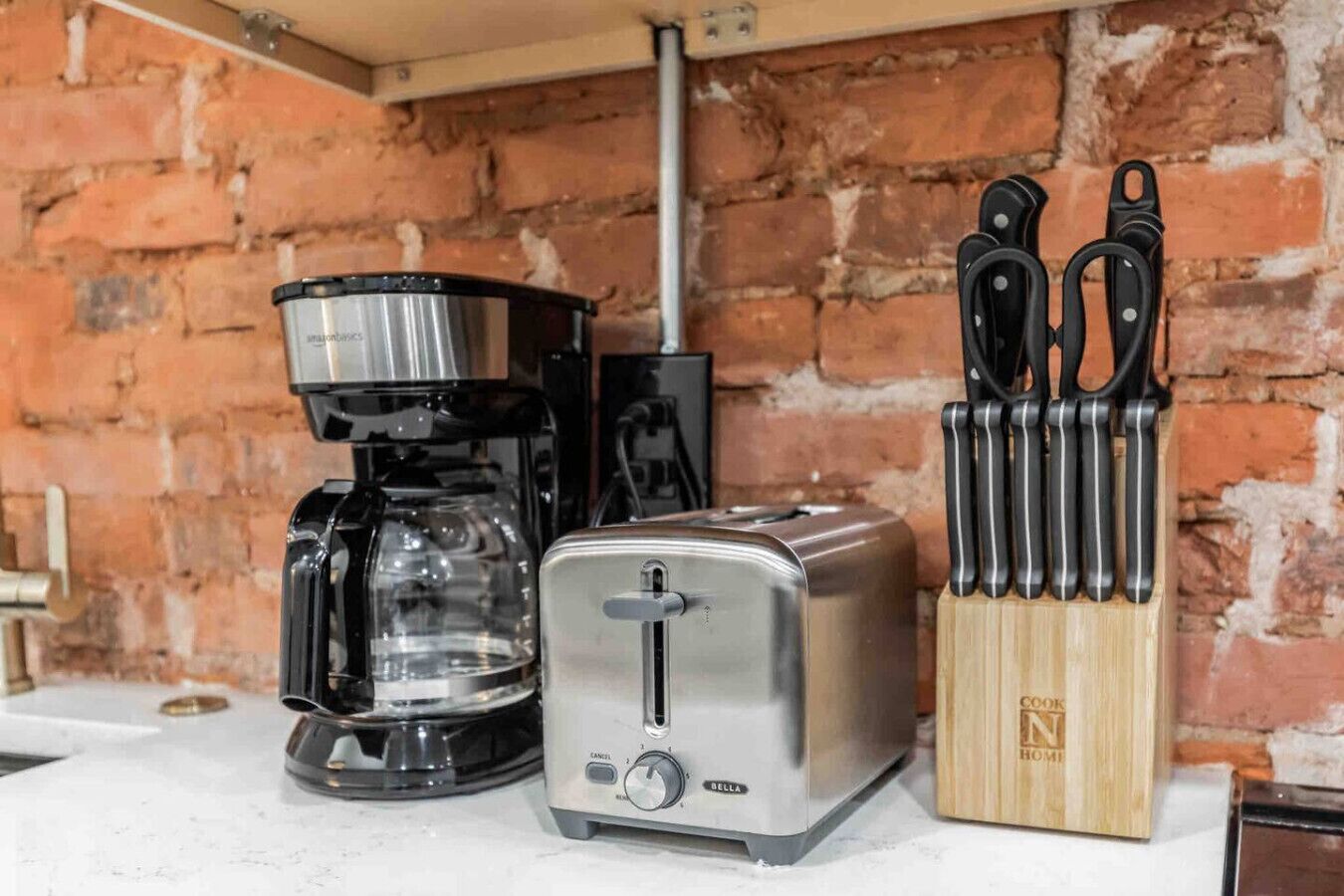 Une cuisine équipée d’une machine à café, d’un grille-pain et d’un bloc à couteaux posé sur le plan de travail.