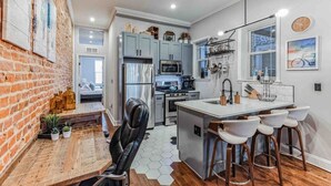 A modern kitchen with grey cabinets, stainless steel appliances, and a central island with bar stools. - Large Bi-Level 3/2 w/Patio | 10 min to DT (Philadelphia)