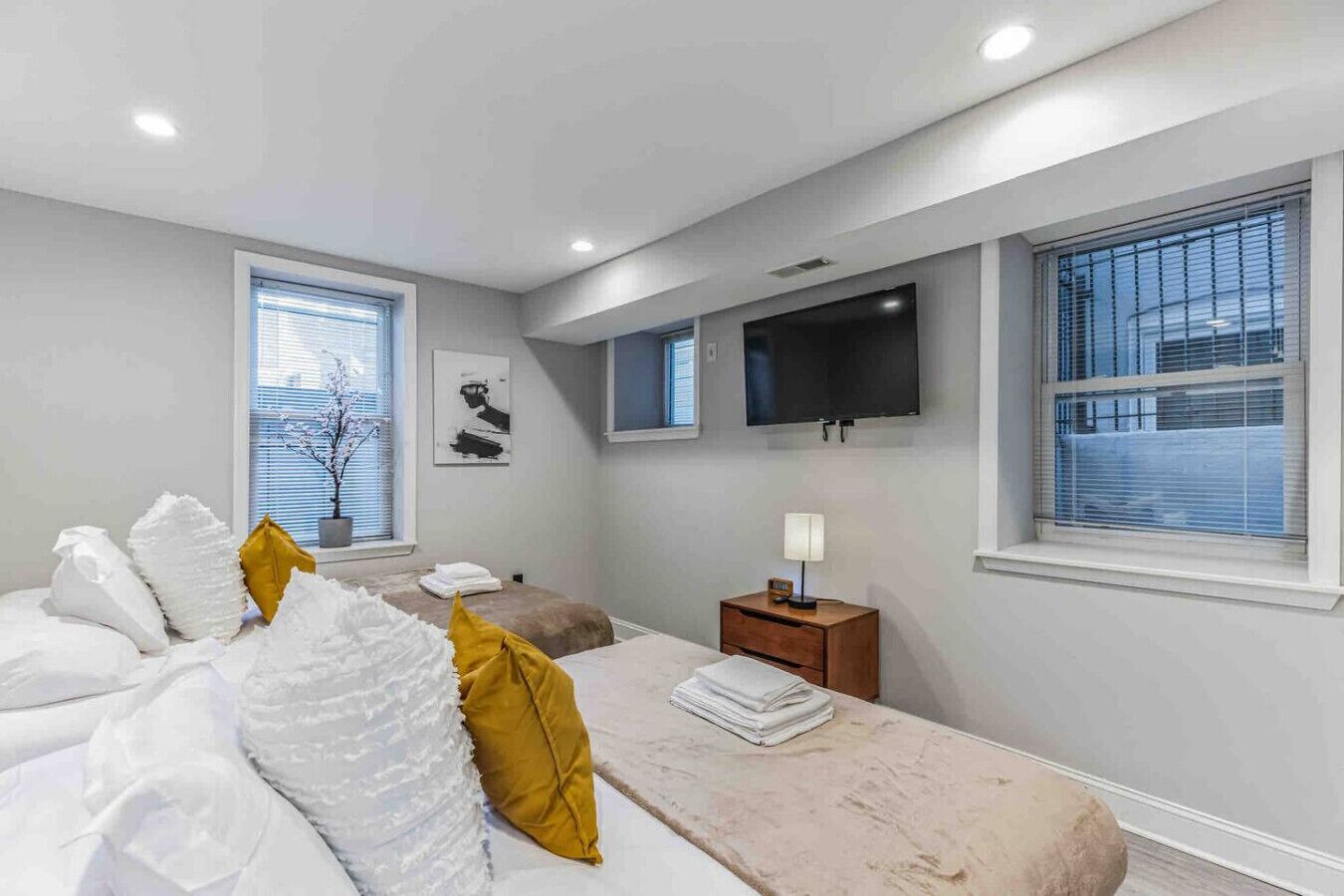 A modern bedroom with a bed, bedside tables, a TV, and large windows.