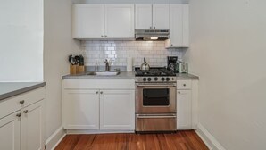 A compact kitchen with white cabinets, a stainless steel stove, and a sink.