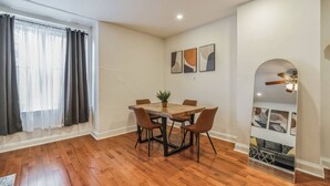 A dining area with a wooden table and chairs, a potted plant, and artwork on the wall.