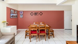 A dining area with a table set for four, surrounded by chairs with red cushions. - Beautiful Apartments in the Center of Floripa - CPN (Florianópolis)