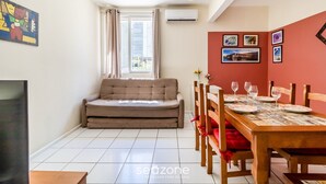 A compact living space with a sofa, dining table, chairs, and artwork on the walls. - Beautiful Apartments in the Center of Floripa - CPN (Florianópolis)
