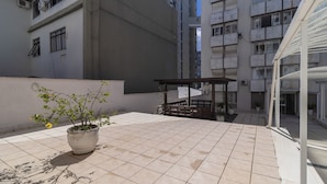 A rooftop terrace with tiled flooring, a potted plant, and a wooden pergola. - Beautiful Apartments in the Center of Floripa - CPN (Florianópolis)