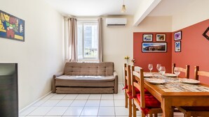 A compact living space with a sofa, dining table, chairs, and artwork on the walls. - Beautiful Apartments in the Center of Floripa - CPN (Florianópolis)