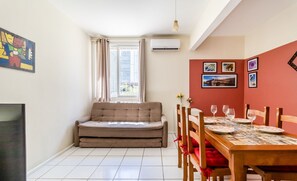 A compact living space with a sofa, dining table, chairs, and artwork on the walls.