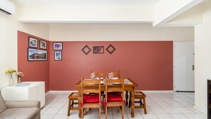 A dining area with a table set for four, surrounded by chairs with red cushions. - Beautiful Apartments in the Center of Floripa - CPN (Florianópolis)