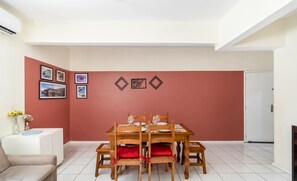 A dining area with a table set for four, surrounded by chairs with red cushions.