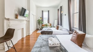 Una habitació d'hotel amb un llit gran, un sofà, una televisió penjada a la paret i una llar de foc.