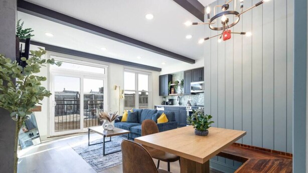 Eine moderne Küche mit grauen Schränken, einem Holzespeisetisch und einem blauen Sofa.