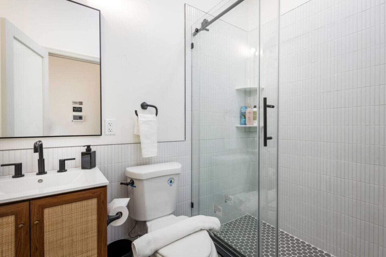 A modern bathroom with a glass shower enclosure, a white toilet, and a vanity with a mirror.
