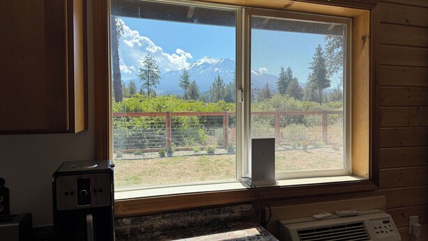 A room with a large window overlooking a garden and a mountain. - Charming 2-bedroom house private setting with amazing Mt. Shasta view (Weed)