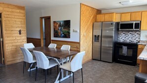 A modern kitchen with a wooden dining area, stainless steel appliances, and a tiled backsplash. - Charming 2-bedroom house private setting with amazing Mt. Shasta view (Weed)