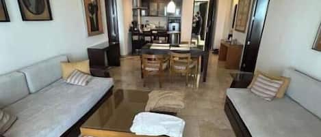 Amplia sala de estar con dos sofás, una mesa de centro y un comedor al fondo.