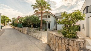 A residential street with a two-story house featuring a balcony, stone walls, and a paved driveway. - Cozy apartment in Vir with WiFi (Vir)