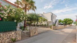 A modern two-story house with a stone wall and metal gate, a paved driveway, and a clear sky. - Cozy apartment in Vir with WiFi (Vir)