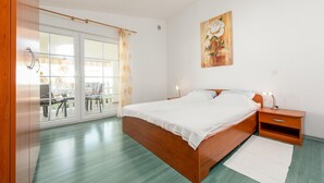 A bedroom with a wooden bed, a nightstand, a lamp, and a painting on the wall. - Cozy apartment in Vir with WiFi (Vir)