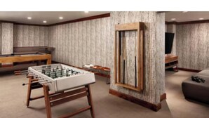A room with a foosball table, a pool table, and a television on a wooden stand. - The Ritz-Carlton Club, Vail (Vail)