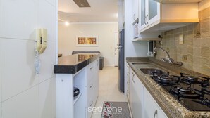 Una cocina moderna con armarios blancos, estufa a gas, un lavamanos y un teléfono.