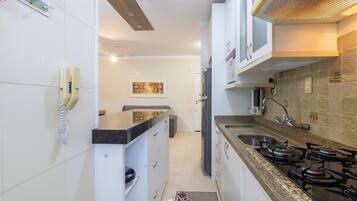 A modern kitchen with white cabinets, a gas stove, a sink, and a telephone.