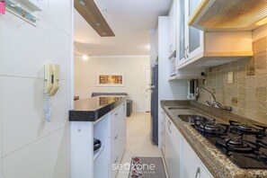 A modern kitchen with white cabinets, a gas stove, a sink, and a telephone.