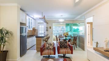 Una cocina moderna con refrigerador, estufa y comedor con sillas y una mesa.