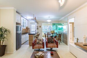 Una cocina moderna con refrigerador, estufa y comedor con sillas y una mesa.