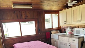 Una cocina compacta con armarios de madera, un microondas y una mesa con mantel a cuadros.