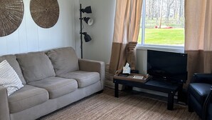Una sala de estar con un sofá, una mesa de centro, un televisor y una lámpara.