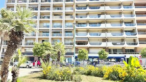 A multi-story residential building with balconies, a parking area, and a small garden with yellow flowers. - 100M FROM THE CASINO, LOVELY 3-ROOM APARTMENT WITH SEA VIEW AND BIJOU GARDENS. PRIVATE PARKING. (Menton)