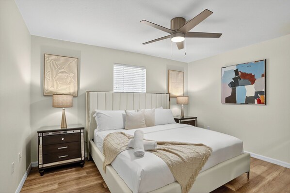A bedroom with a bed, nightstands, a ceiling fan, and artwork on the walls. - 9BR Pool & Spa Villa w/ Star Wars Arcade & Theater (Kissimmee)