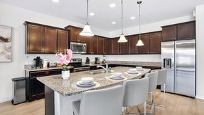 Una cocina moderna con encimeras de granito, electrodomésticos de acero inoxidable y una isla central con asientos tipo barra.