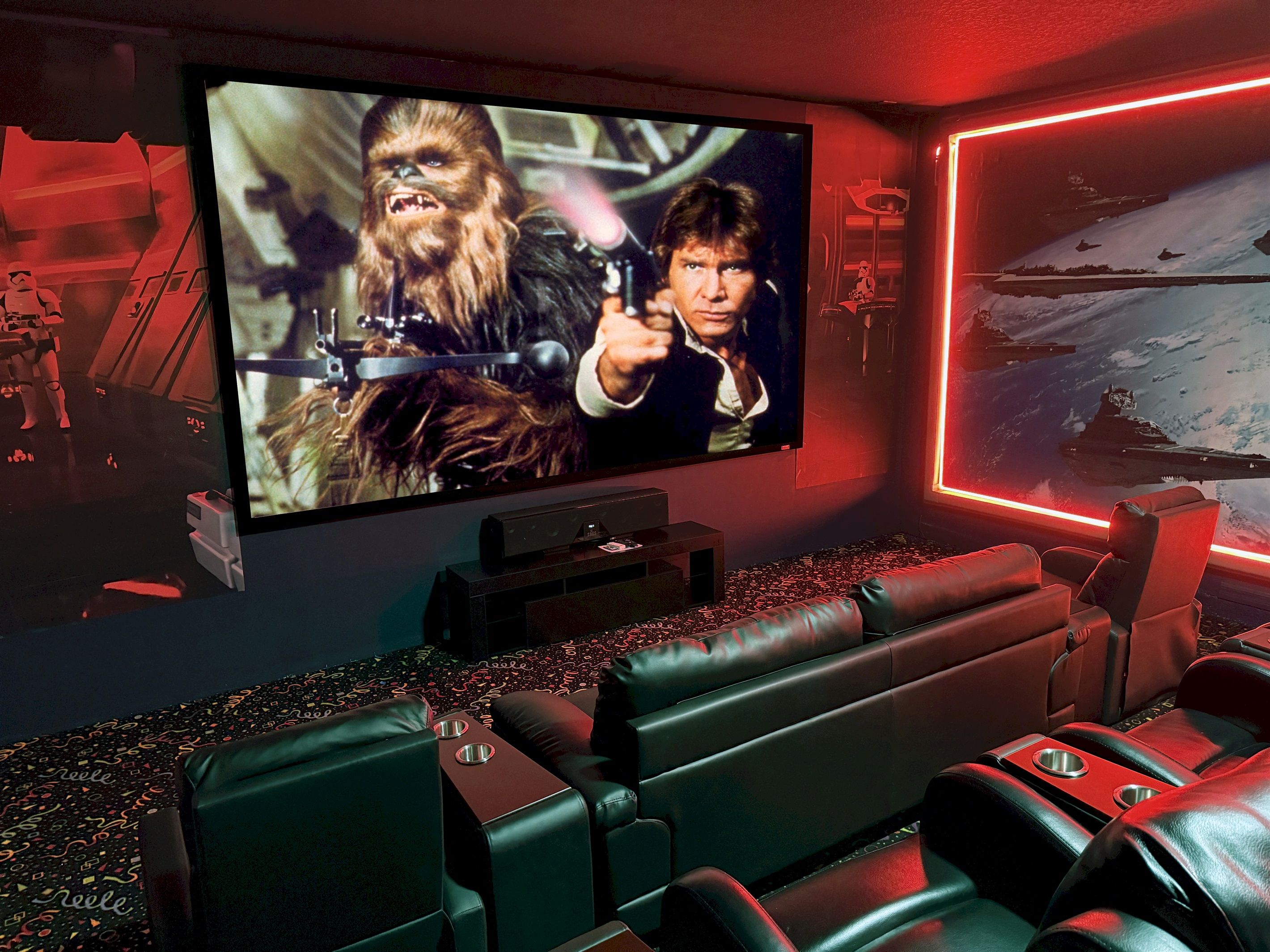 A home theater with a large screen, leather seating, and a Star Wars-themed wall.