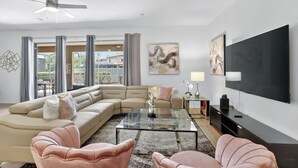 Una sala moderna con un sofá modular, una mesa de centro de vidrio y sillones rosados.
