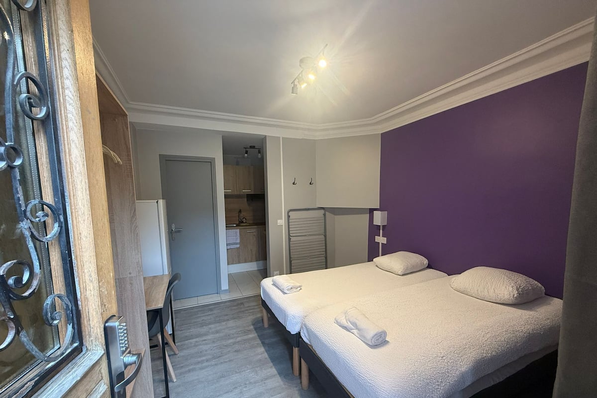 A bedroom with a bed, a desk, and a wardrobe.