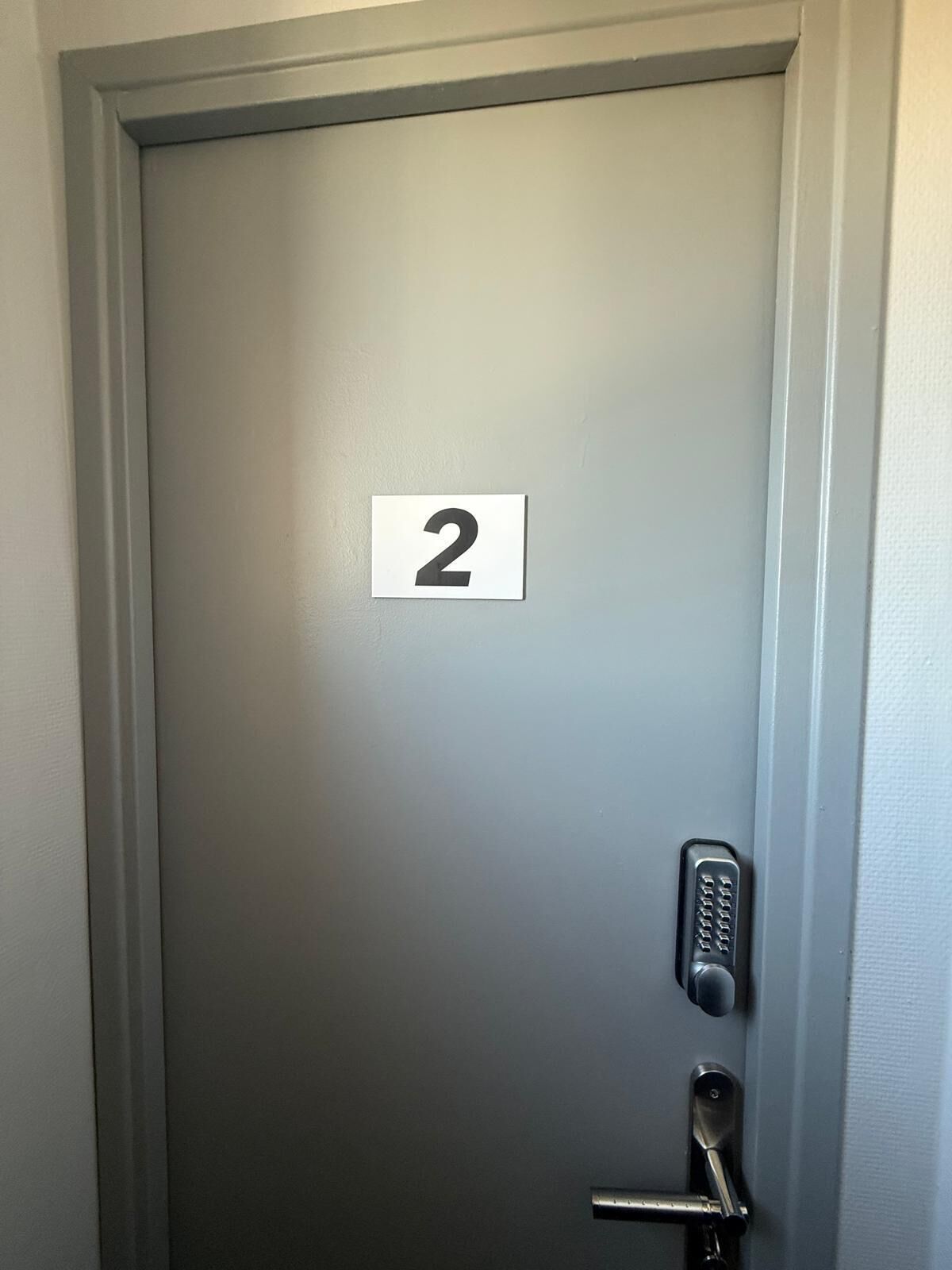 Una puerta con un letrero con el número 2, una cerradura y un picaporte.