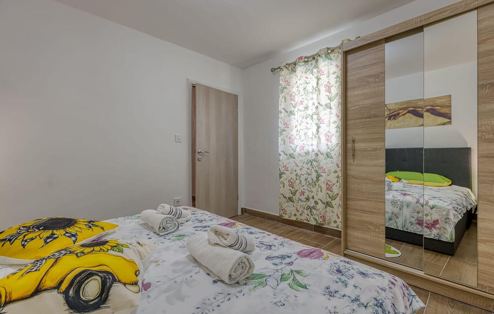 Una camera da letto con un letto, uno specchio grande, un armadio e una porta.